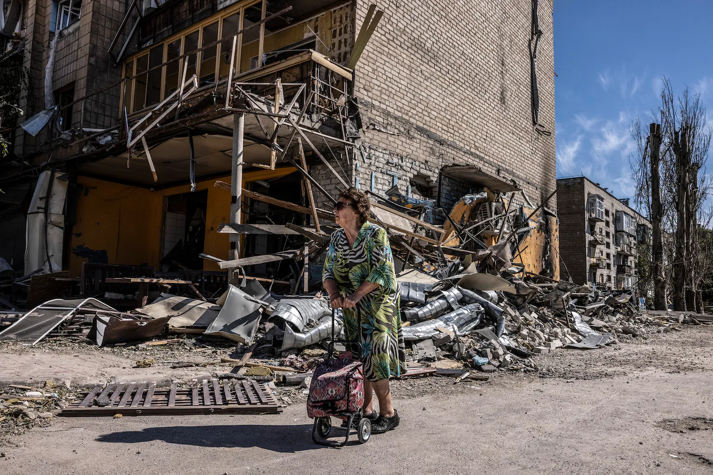 Світлана Жданова робить паузу під час прогулянки біля зруйнованого російськими ракетними ударами ресторану в Покровську.